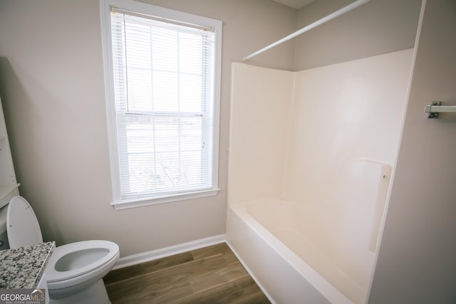 bathroom featuring toilet, baseboards, wood finished floors, and shower / bathtub combination