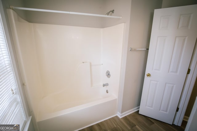 bathroom featuring baseboards, wood finished floors, and shower / bathtub combination