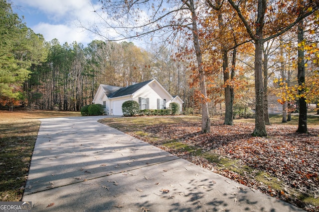 view of front facade featuring a garage, a wooded view, and concrete driveway