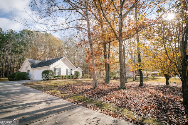 view of property exterior featuring an attached garage and concrete driveway