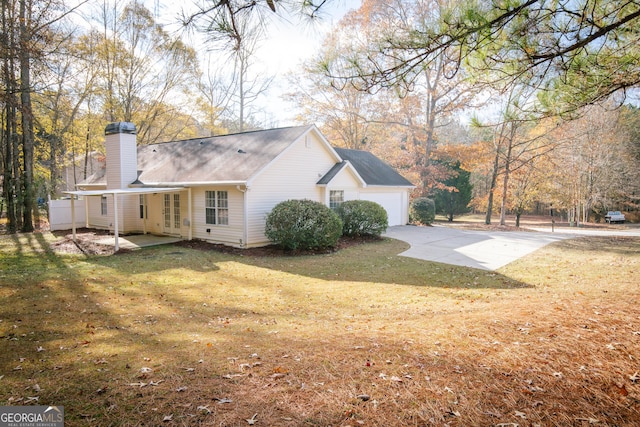 exterior space with driveway, an attached garage, a chimney, and a lawn