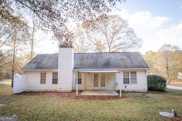 rear view of property featuring a yard, french doors, roof with shingles, a chimney, and a patio area