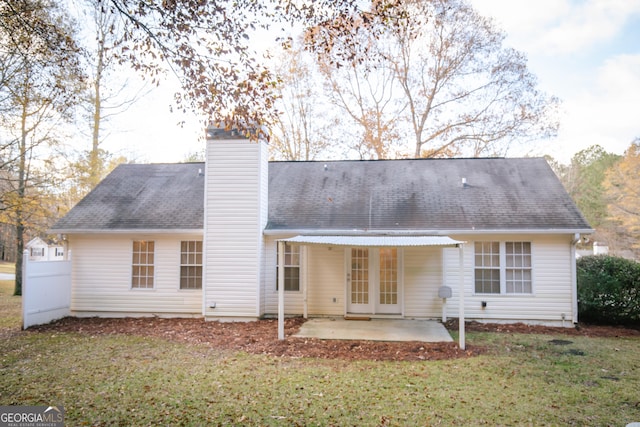 rear view of property with a patio area, a lawn, a chimney, and roof with shingles