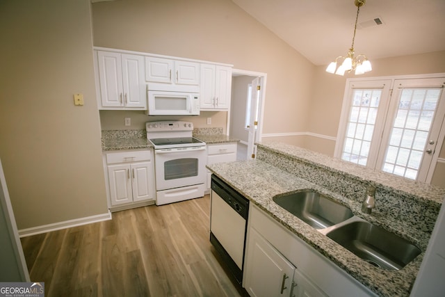 kitchen featuring white appliances, a sink, white cabinets, vaulted ceiling, and light wood finished floors