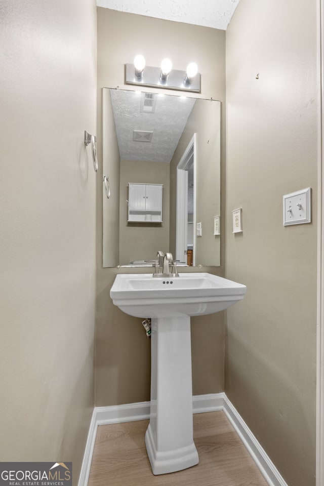 bathroom with a sink, baseboards, and wood finished floors