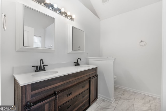 bathroom with vaulted ceiling, marble finish floor, a sink, and baseboards