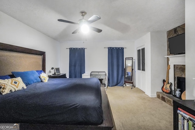 bedroom with carpet floors, a fireplace with raised hearth, ceiling fan, and a textured ceiling