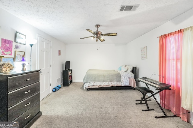 carpeted bedroom featuring a textured ceiling, ceiling fan, and visible vents