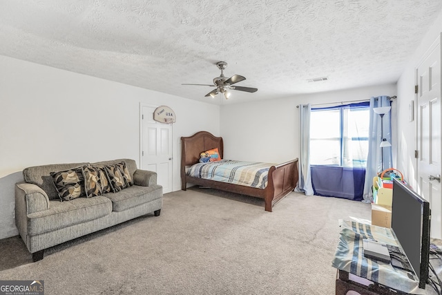 bedroom with ceiling fan, a textured ceiling, carpet flooring, and visible vents