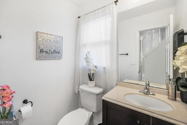 half bath featuring toilet, vanity, and a wealth of natural light