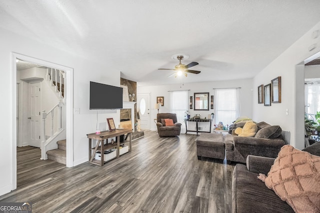 living room featuring ceiling fan, stairway, wood finished floors, and a textured ceiling