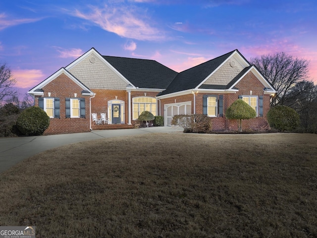 view of front of house with driveway, a yard, an attached garage, and brick siding