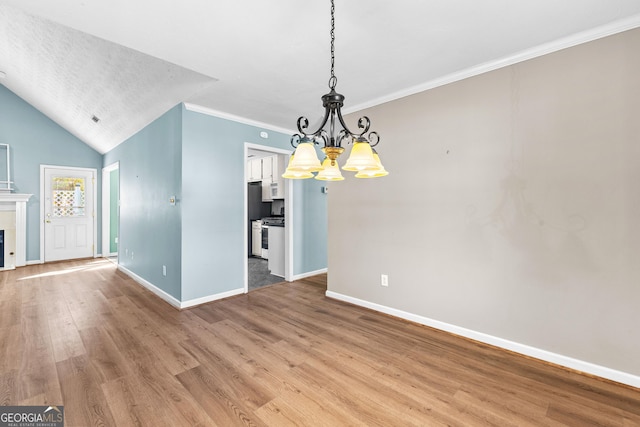 unfurnished dining area featuring baseboards, a tiled fireplace, an inviting chandelier, crown molding, and light wood-style floors