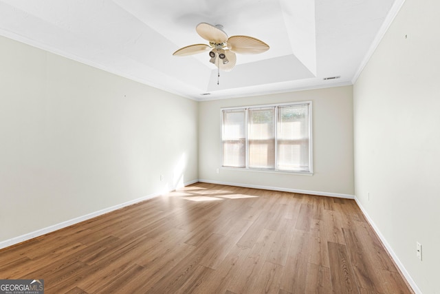 spare room featuring a ceiling fan, baseboards, a raised ceiling, and wood finished floors