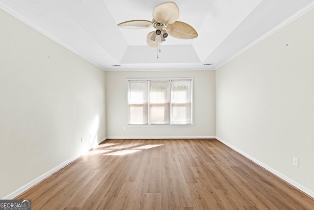 empty room featuring baseboards, a tray ceiling, a ceiling fan, and light wood-style floors