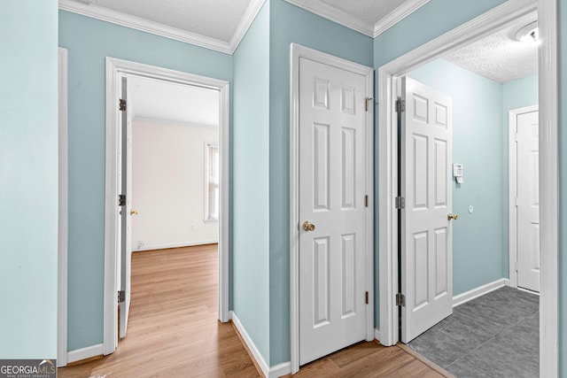 hall with baseboards, light wood-type flooring, and crown molding