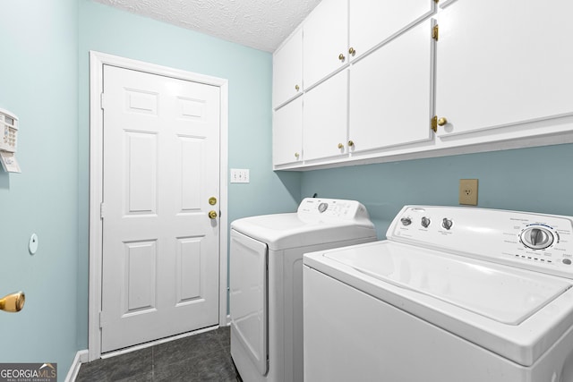 laundry room featuring cabinet space, a textured ceiling, washing machine and clothes dryer, and dark tile patterned floors