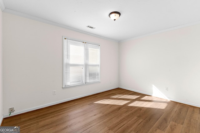 unfurnished room featuring baseboards, wood finished floors, visible vents, and crown molding