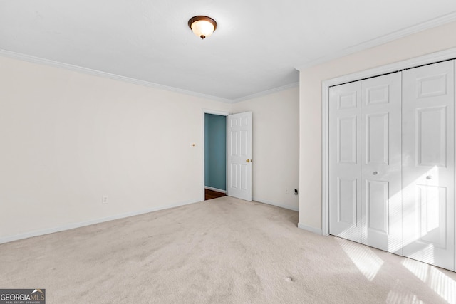 unfurnished bedroom featuring crown molding, a closet, baseboards, and carpet flooring