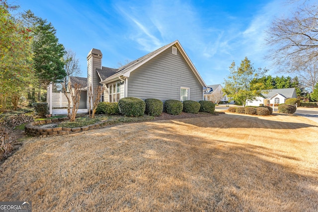 view of home's exterior with a chimney and a yard