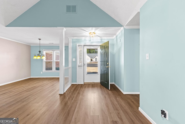 entryway with wood finished floors, visible vents, and crown molding