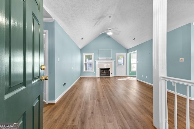 unfurnished living room with a textured ceiling, ceiling fan, a fireplace, and wood finished floors