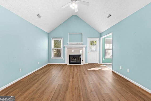 unfurnished living room featuring a fireplace with flush hearth, a textured ceiling, visible vents, and wood finished floors