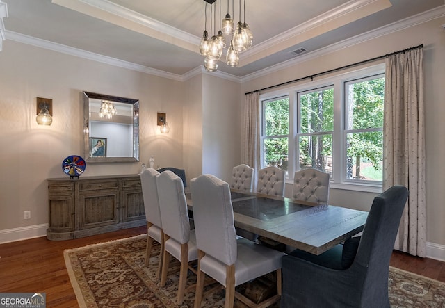 dining space featuring baseboards, visible vents, a tray ceiling, and wood finished floors