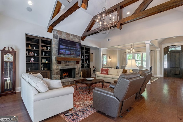 living room with ornate columns, a chandelier, dark wood finished floors, and a stone fireplace