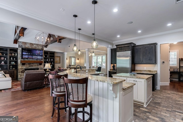 kitchen with built in fridge, a spacious island, a kitchen breakfast bar, open floor plan, and crown molding