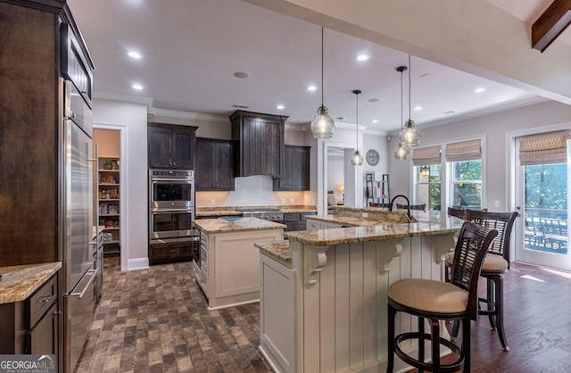 kitchen featuring dark brown cabinetry, recessed lighting, a kitchen breakfast bar, appliances with stainless steel finishes, and a large island