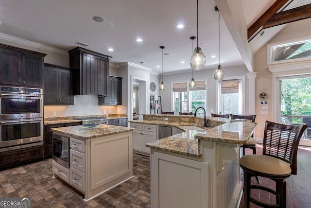 kitchen featuring crown molding, a large island, appliances with stainless steel finishes, a sink, and plenty of natural light