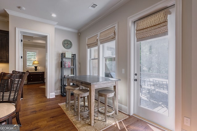 dining room with baseboards, visible vents, ornamental molding, and dark wood-style flooring