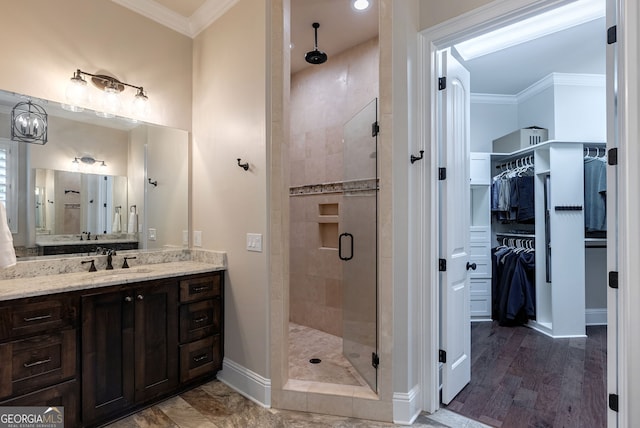 bathroom featuring vanity, baseboards, a stall shower, a walk in closet, and crown molding