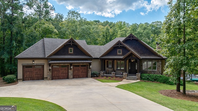 view of front of house featuring a garage, concrete driveway, stone siding, a front lawn, and a view of trees