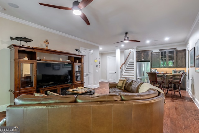 living room with a ceiling fan, crown molding, stairway, and wood finished floors