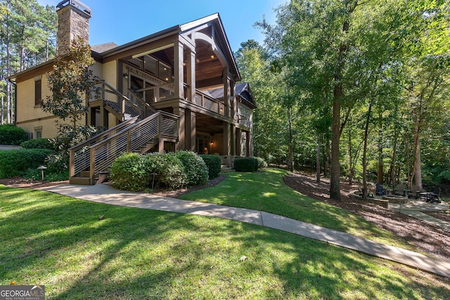 exterior space with a yard, stairway, a chimney, and stucco siding