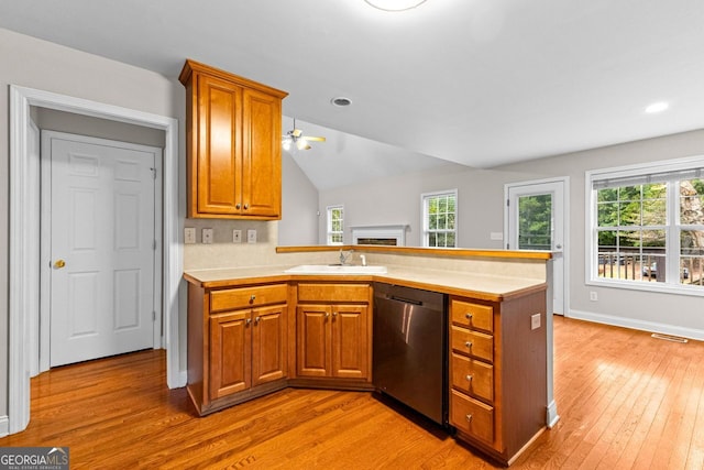 kitchen featuring light countertops, stainless steel dishwasher, brown cabinetry, a sink, and a peninsula