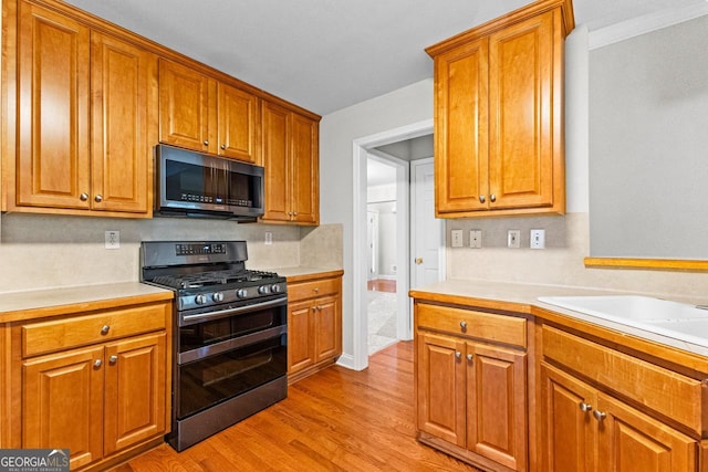 kitchen featuring light wood-style floors, stainless steel microwave, range with two ovens, and light countertops