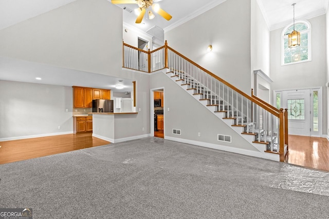 unfurnished living room with stairs, baseboards, a wealth of natural light, and ornamental molding