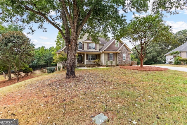 view of front of house with stone siding, fence, and a front yard