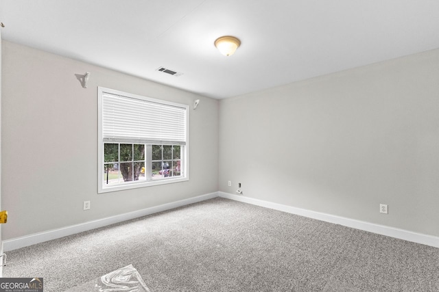 empty room featuring carpet, visible vents, and baseboards