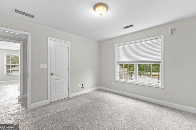 unfurnished room with carpet flooring, visible vents, and baseboards