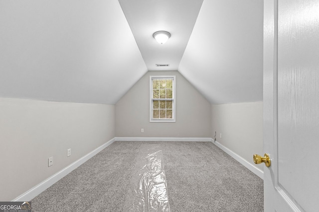 additional living space with carpet floors, baseboards, visible vents, and vaulted ceiling