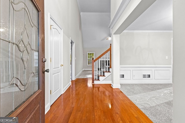 foyer with visible vents, a wainscoted wall, wood finished floors, stairs, and a decorative wall