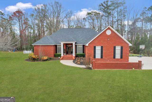 view of front of property with roof with shingles, a front lawn, and brick siding