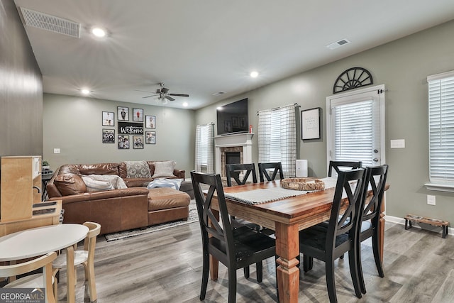 dining area featuring light wood-type flooring, visible vents, and a glass covered fireplace