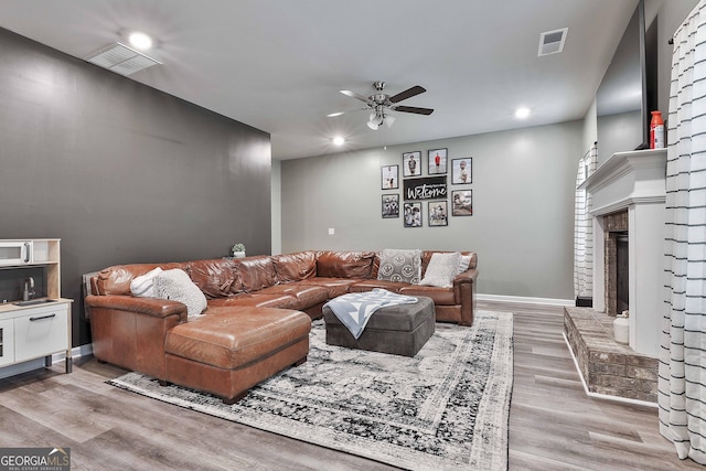 living room with ceiling fan, light wood-type flooring, visible vents, and baseboards