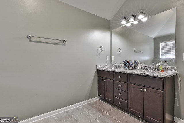 bathroom featuring vaulted ceiling, double vanity, tile patterned flooring, and a sink