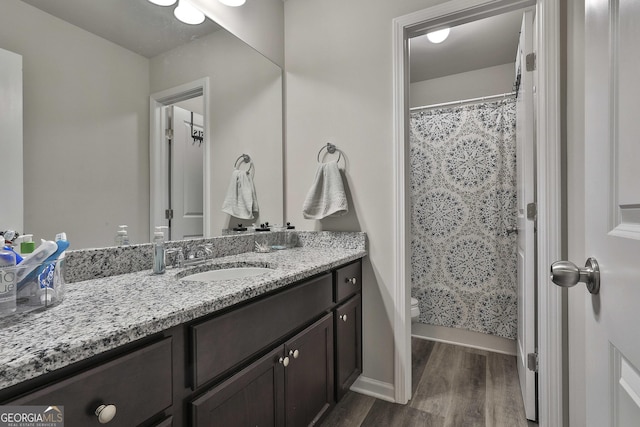 full bathroom with a shower with shower curtain, toilet, vanity, wood finished floors, and baseboards